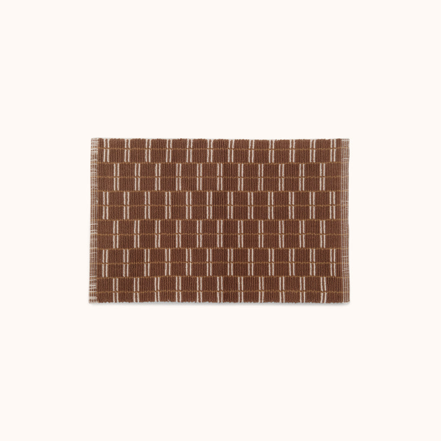 A rectangular brown and natural mat with a geometric pattern.