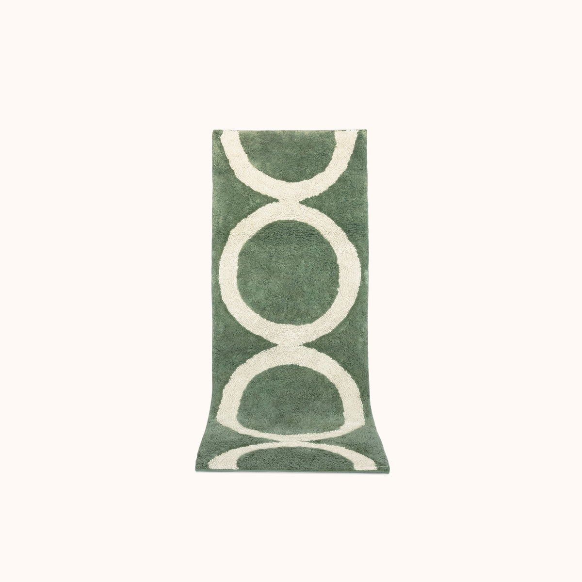 A green and tan geometric designed bath mat made of plush tufted cotton.