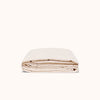 A folded beige duvet cover made of matte sateen cotton against a white background.