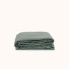 A folded green duvet cover made of matte sateen fabric against a white background