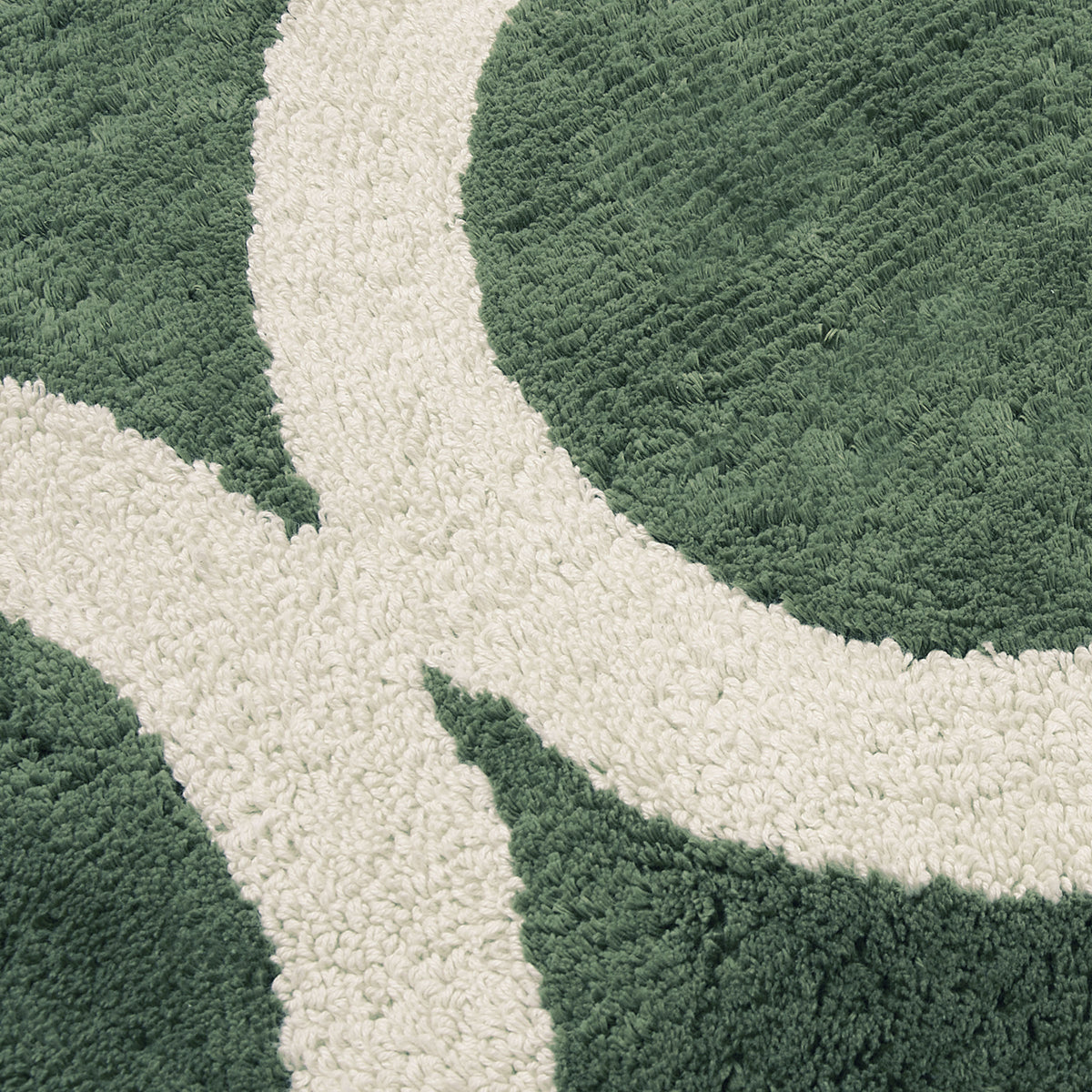 Close up of a green tufted bath runner with a tan circle geometric pattern.