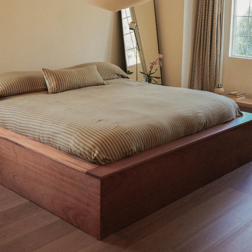 Striped coverlet and pillow on a wooden bed frame
