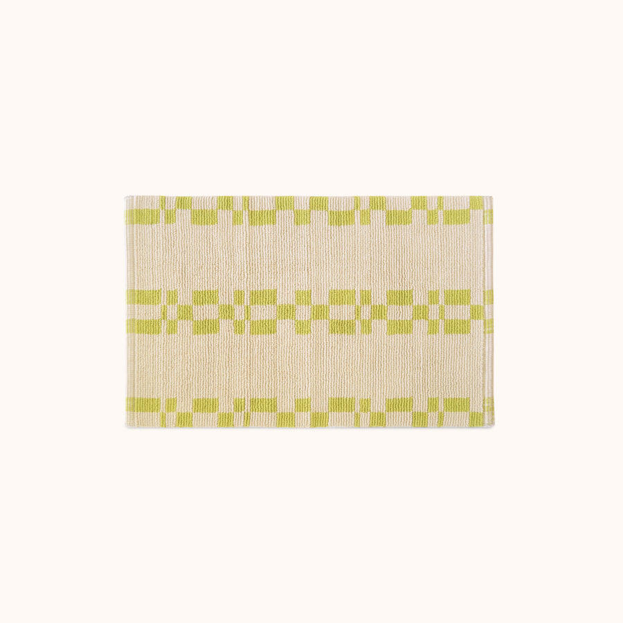 A rectangular, bathmat with a geometric pattern in green and beige colors.