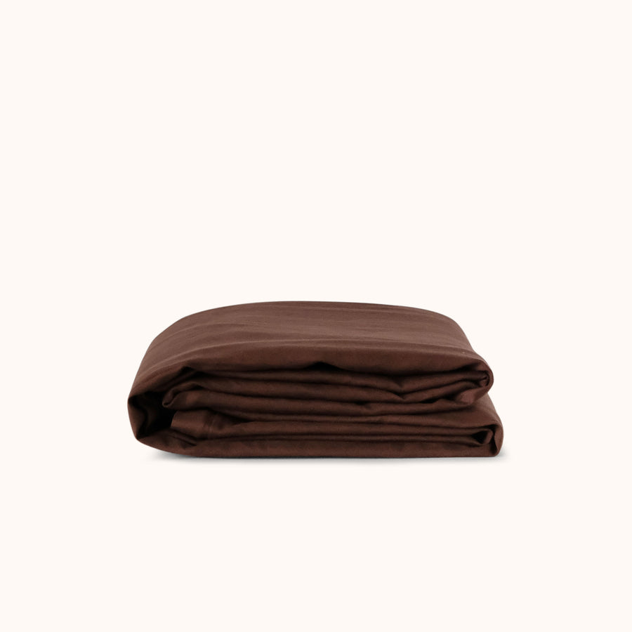 A brown / purple duvet cover folded neatly against a white background 
