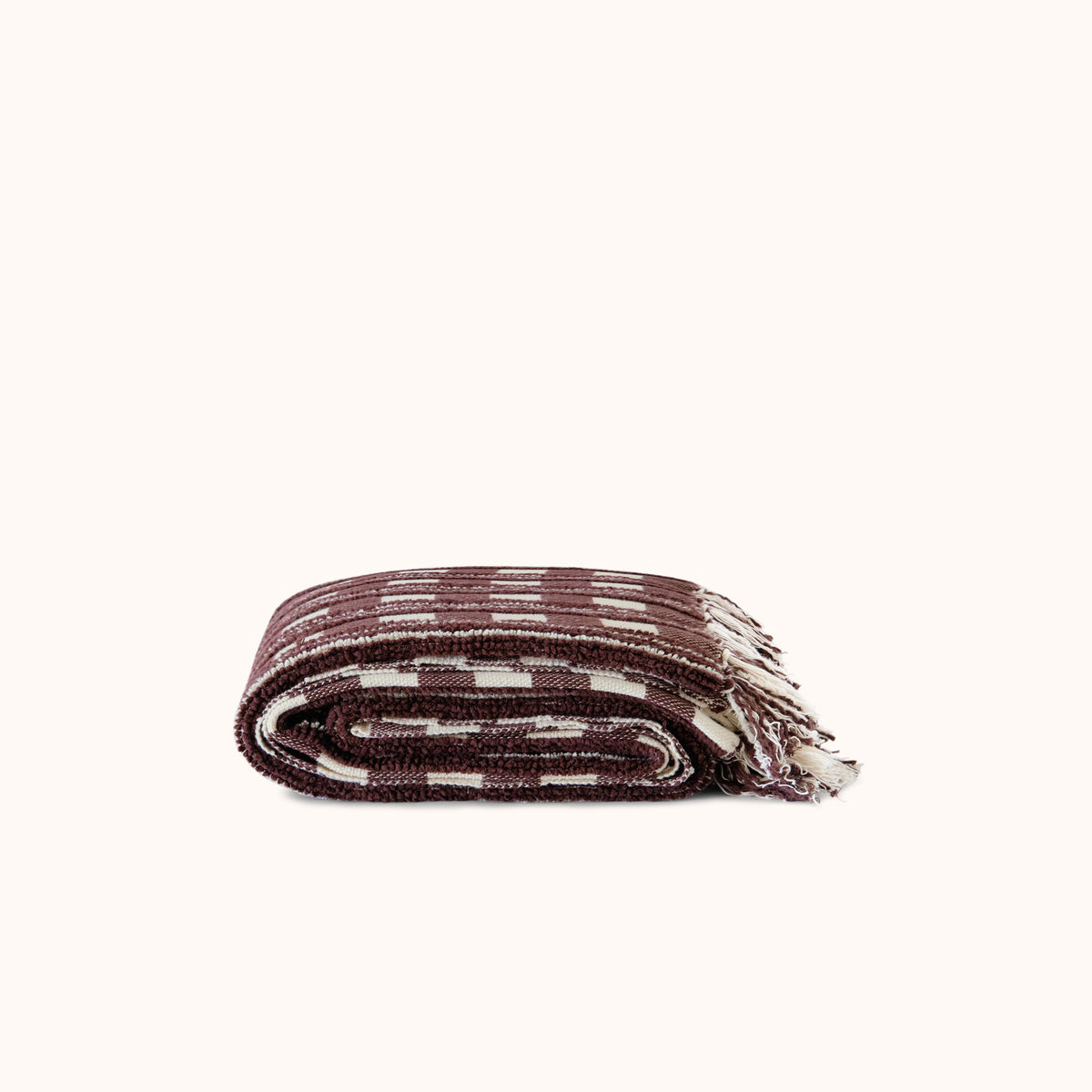 Folded woven blanket with a striped pattern on a white background