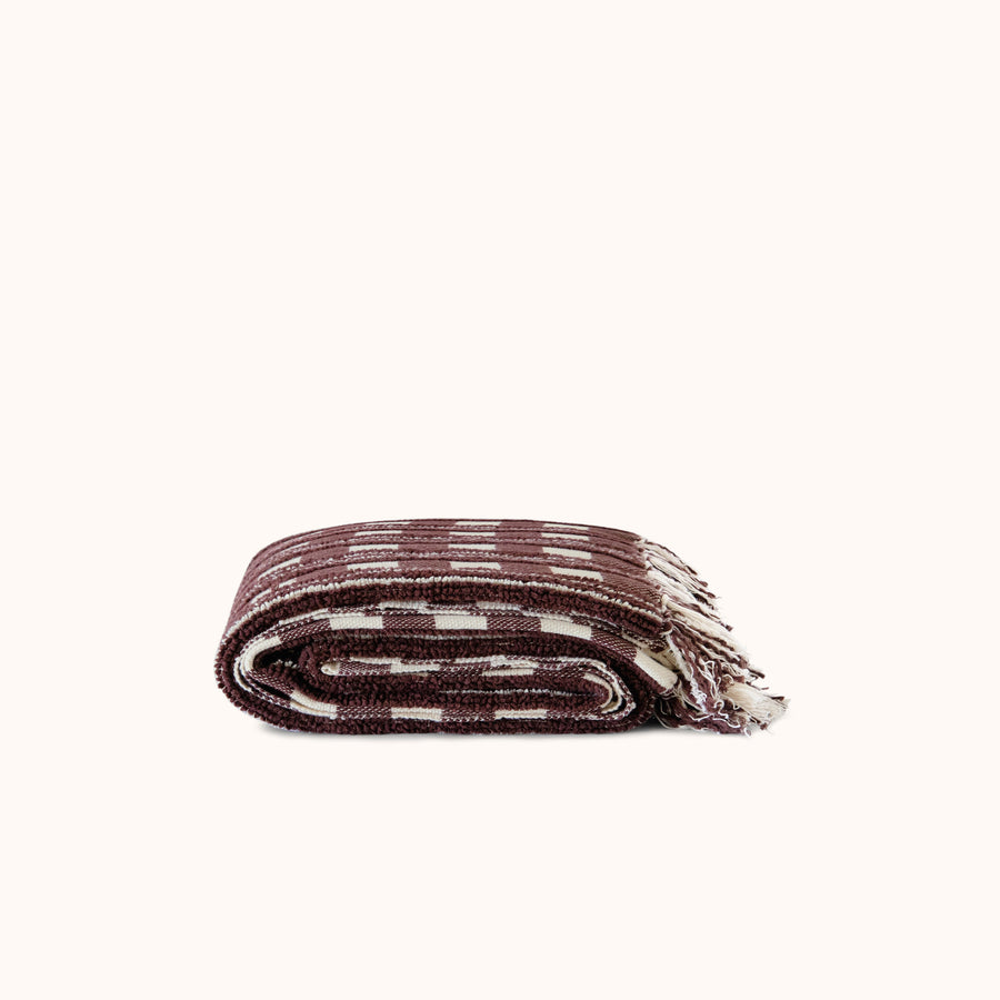 Folded woven blanket with a striped pattern on a white background