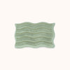 Green textured rectangular bath mat with alternating shag heights on a white background