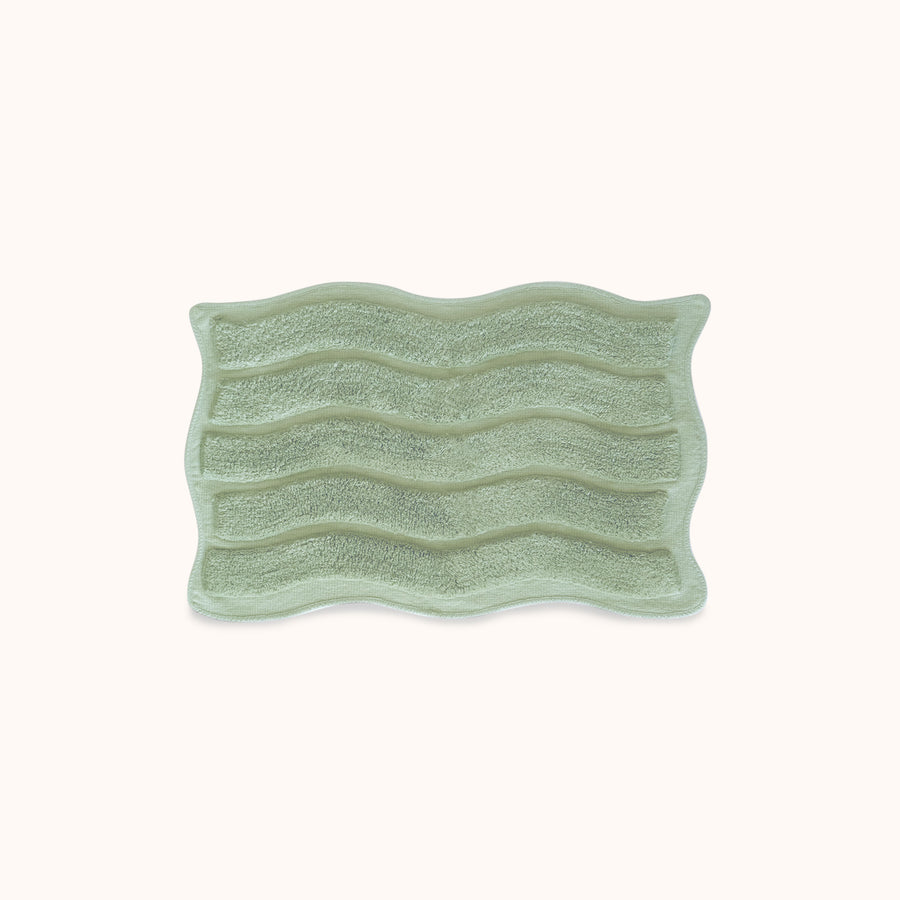 Green textured rectangular bath mat with alternating shag heights on a white background
