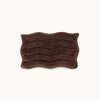 Brown textured bath mat with wavy pattern and alternating shag heights on a white background