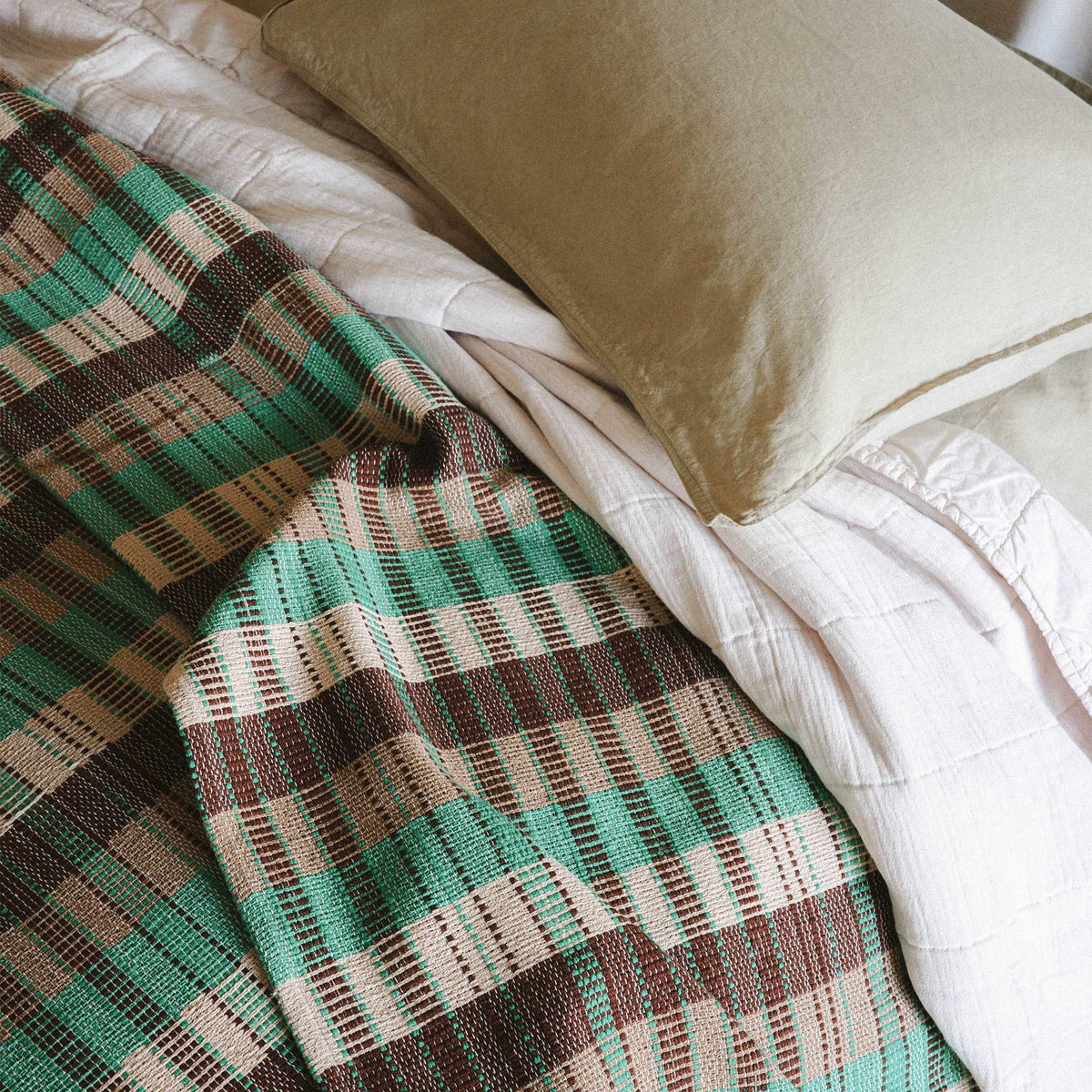 A close up of the details on the Yara blanket, you can see the checkered pattern in green, brown and beige