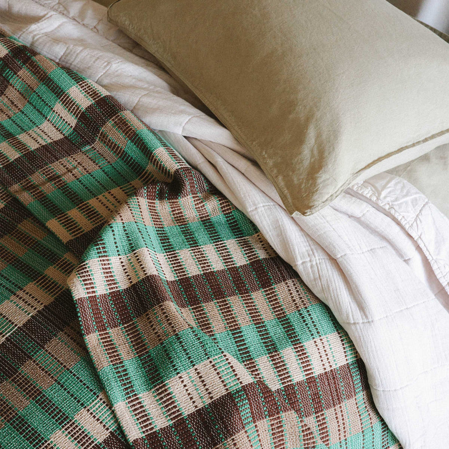 A close up of the details on the Yara blanket, you can see the checkered pattern in green, brown and beige