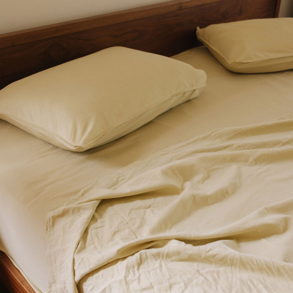 A wooden bed made with Límon / light yellow sheets 