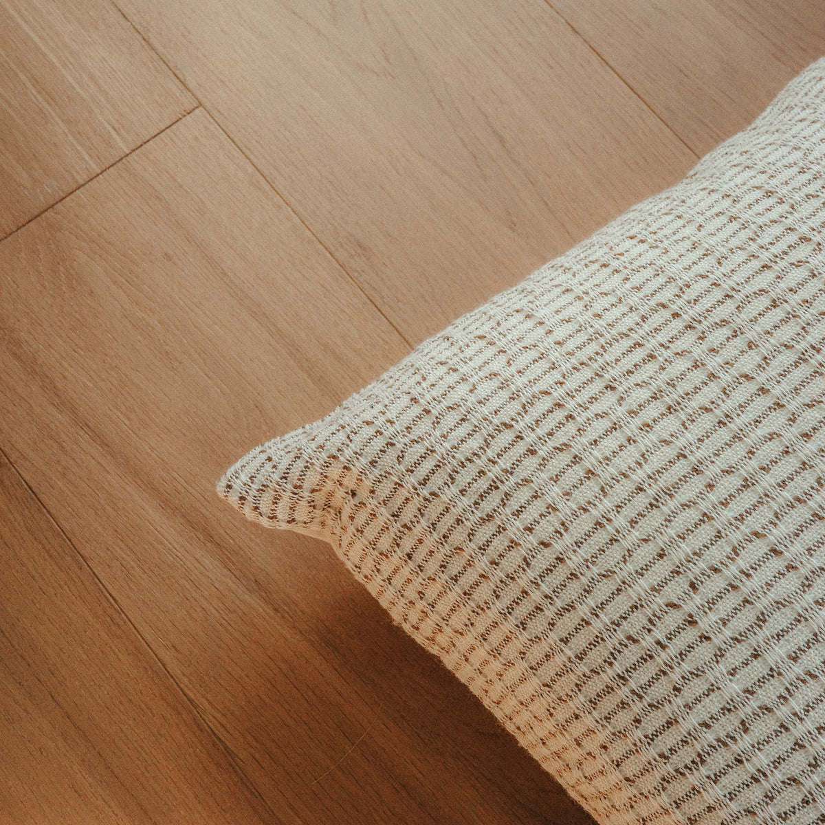 Close up of a throw pillow with a beige and brown hazelnut stripe texture.