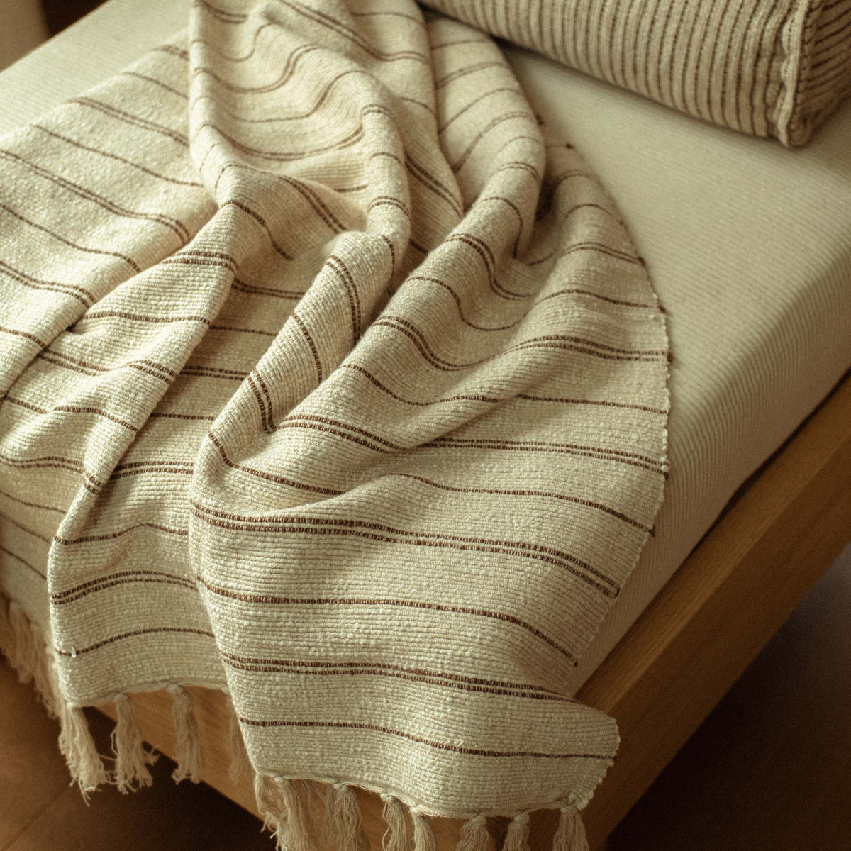 I close up of the Pia blanket which has brown stripes and tassels. The blanket is textured. 