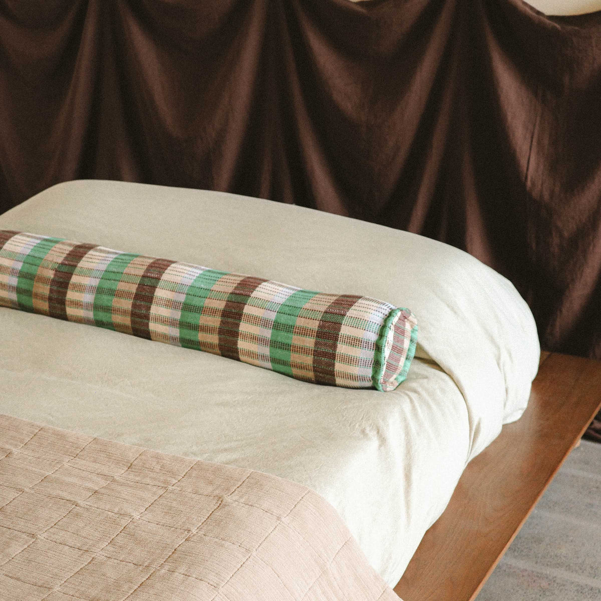 A close up of the Yara bolster on a cream colored bed