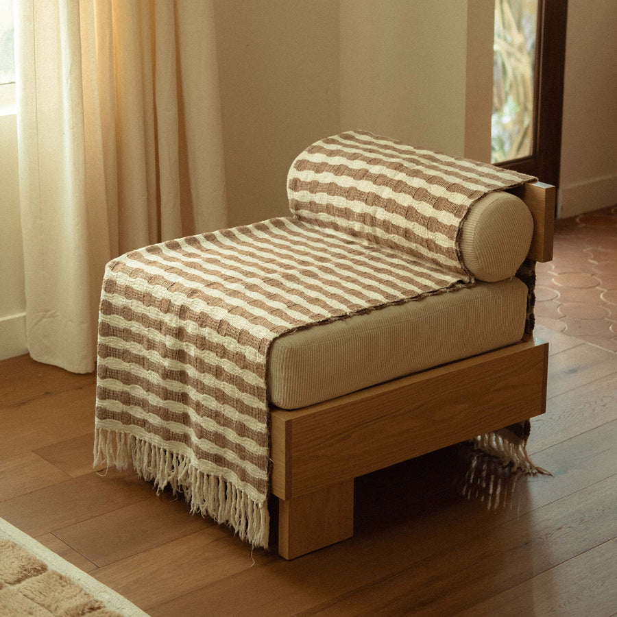 The Ramona folded neatly on a modern accent chair in a living room setting