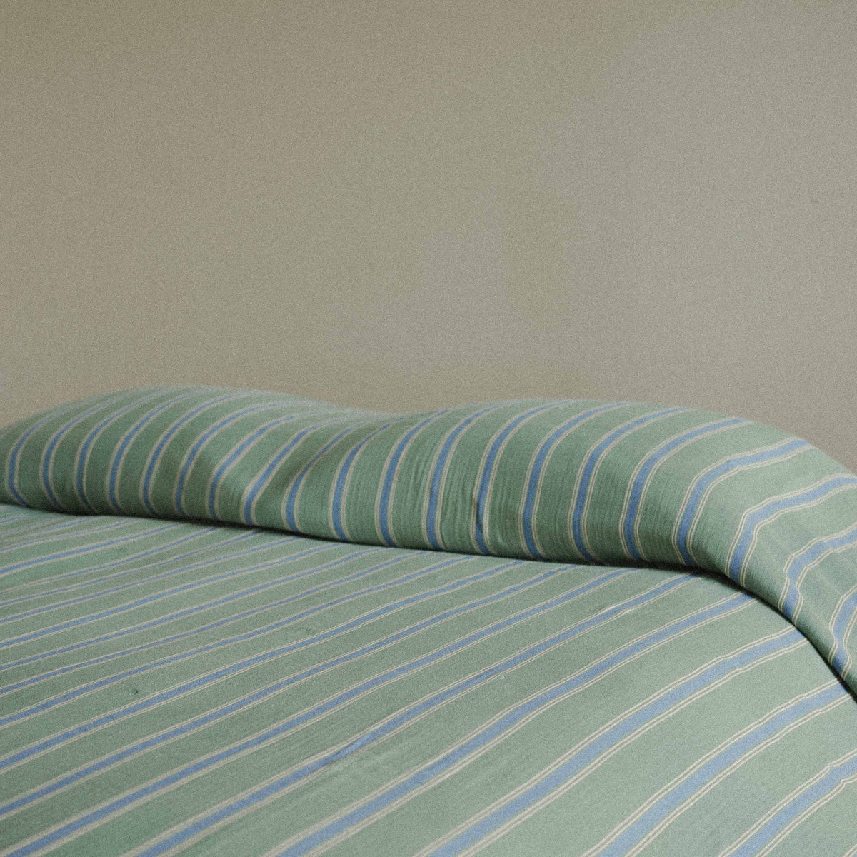 Green and blue striped bedspread on a plain background