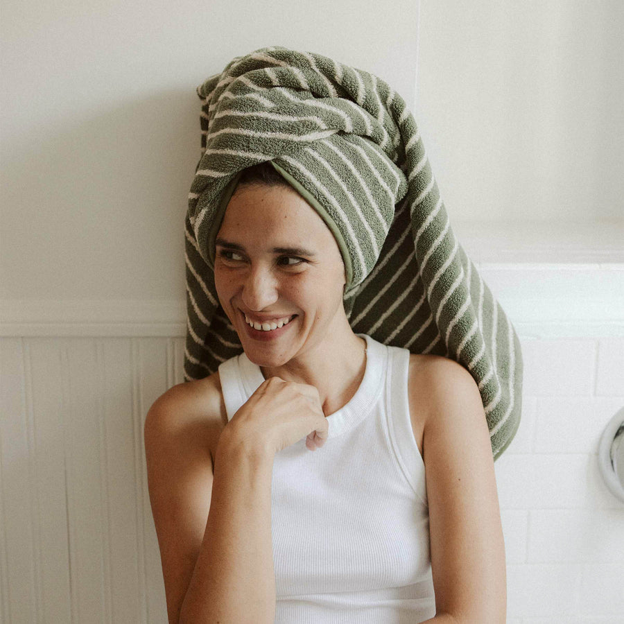 Green and tan striped bath towel wrapped around a woman's hair.