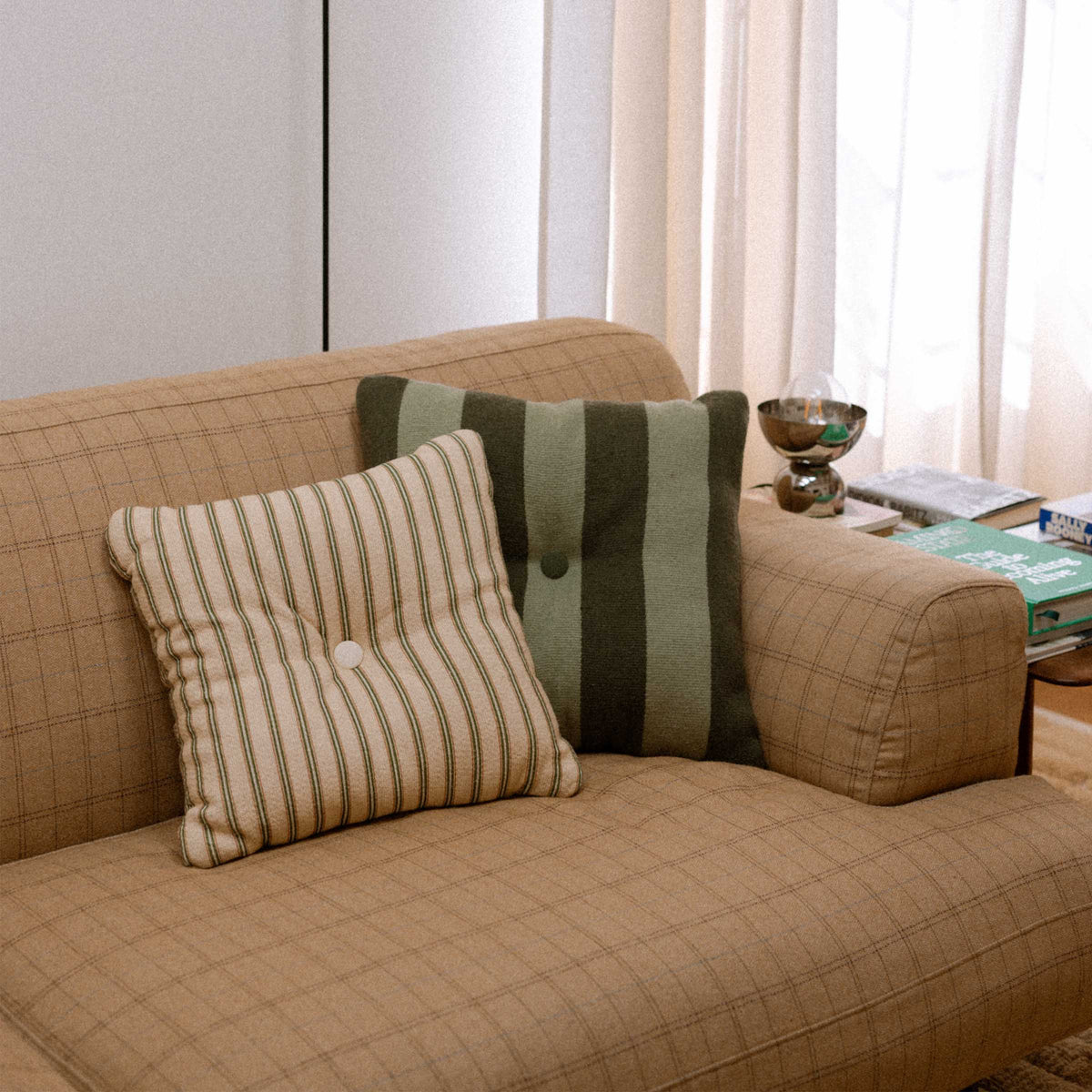Beige sofa with green striped throw pillows in a living room setting