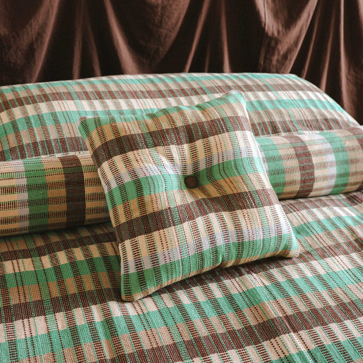 A close up of the Yara throw pillow resting against a Yara bolster and Yara bed cover. 