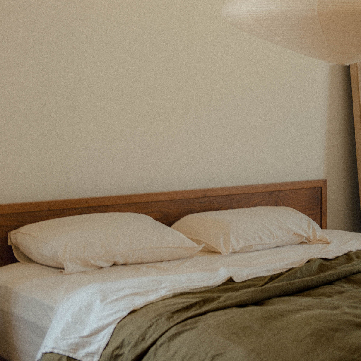 A bed made with two Oat pillows and sheets paired with a Fern duvet cover in a bedroom setting