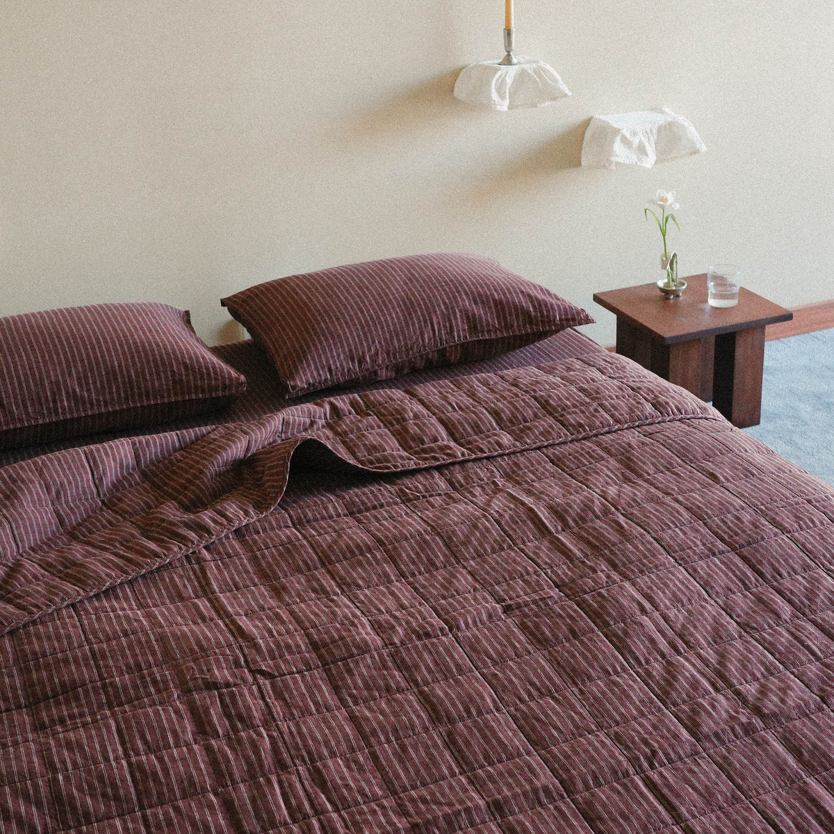 Brown striped quilt / bed cover on a bed with matching pillows in a bright bedroom setting.