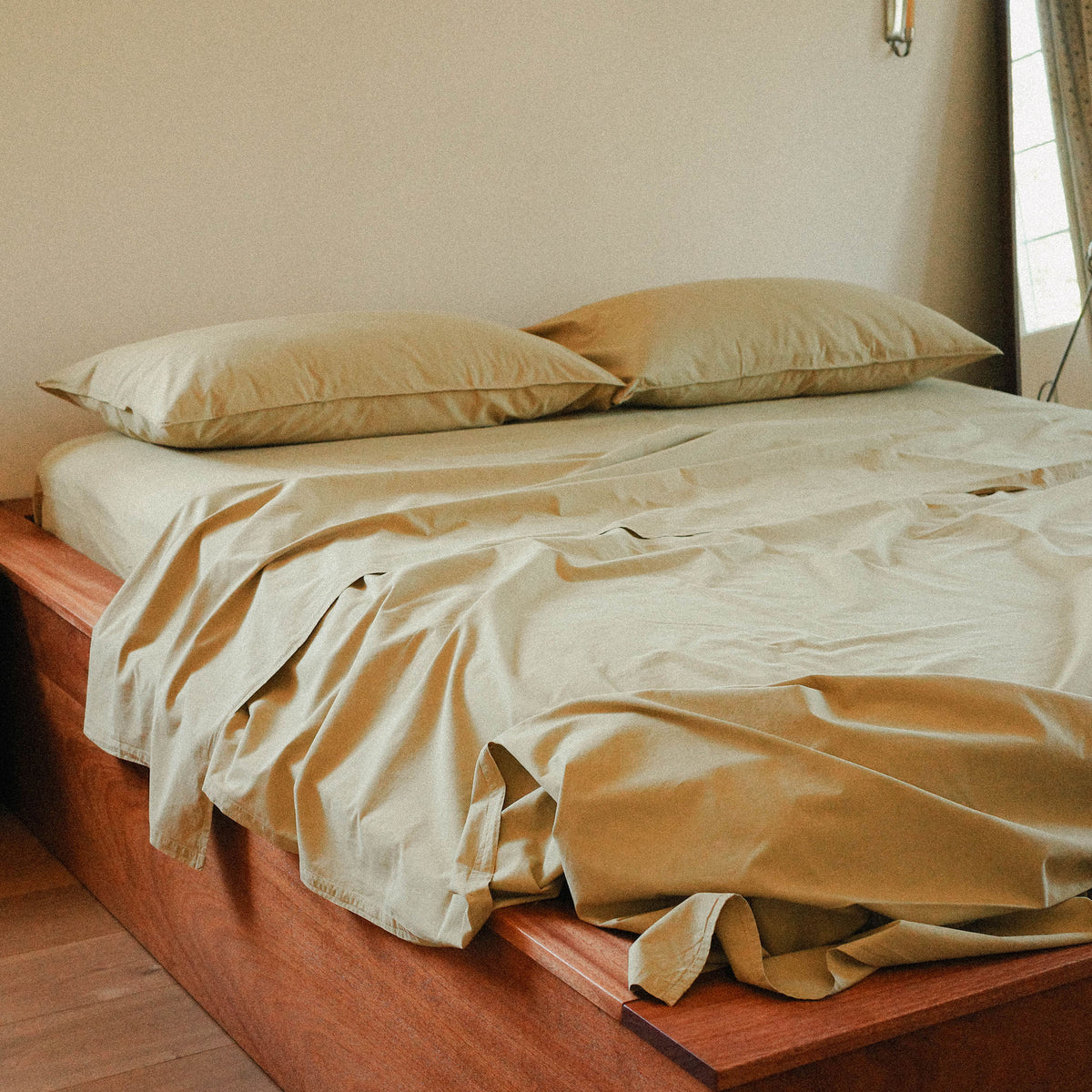 Bed with green bedding and pillows in a room with a mirror.