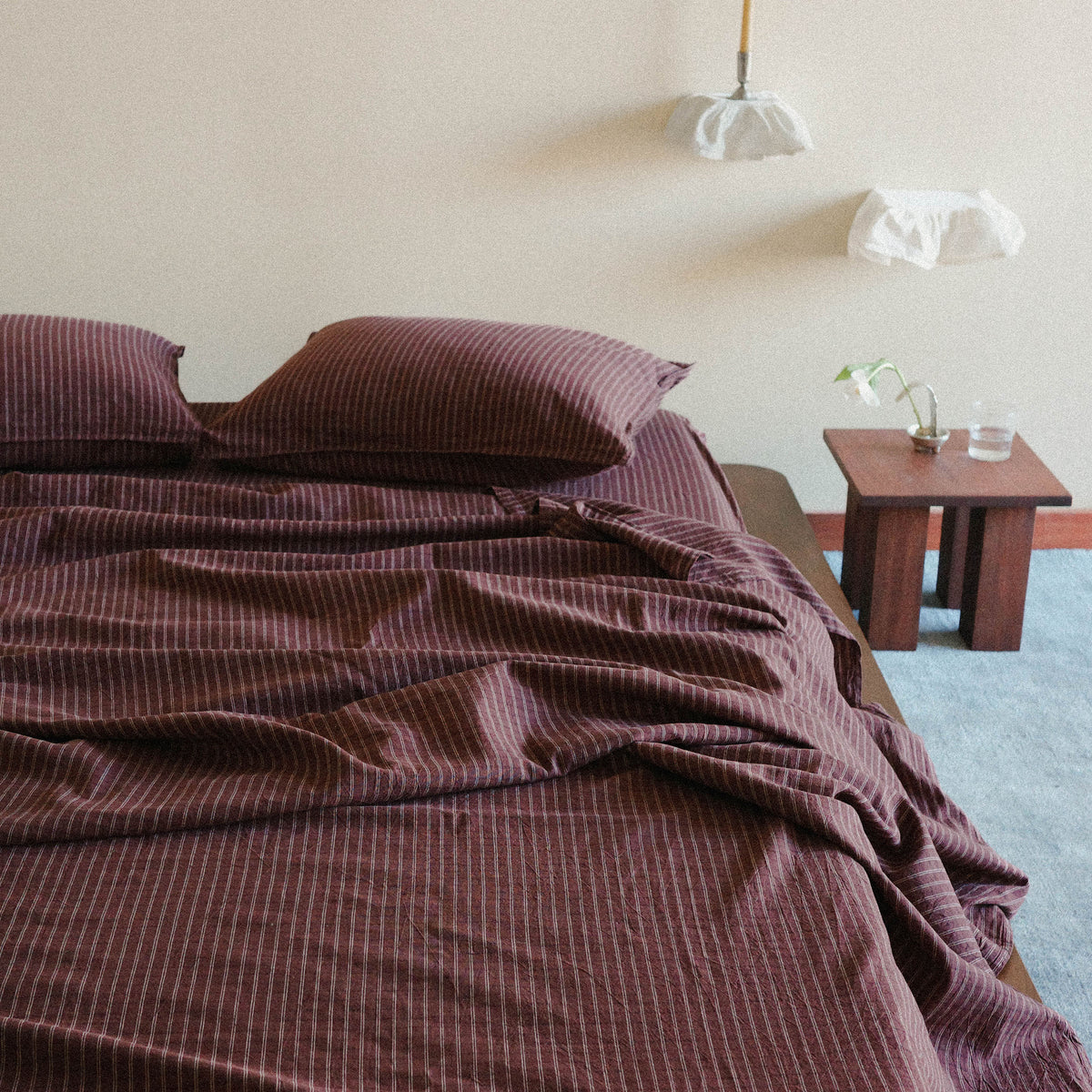 Bed with brown striped bedding in a minimalistic bedroom setting.