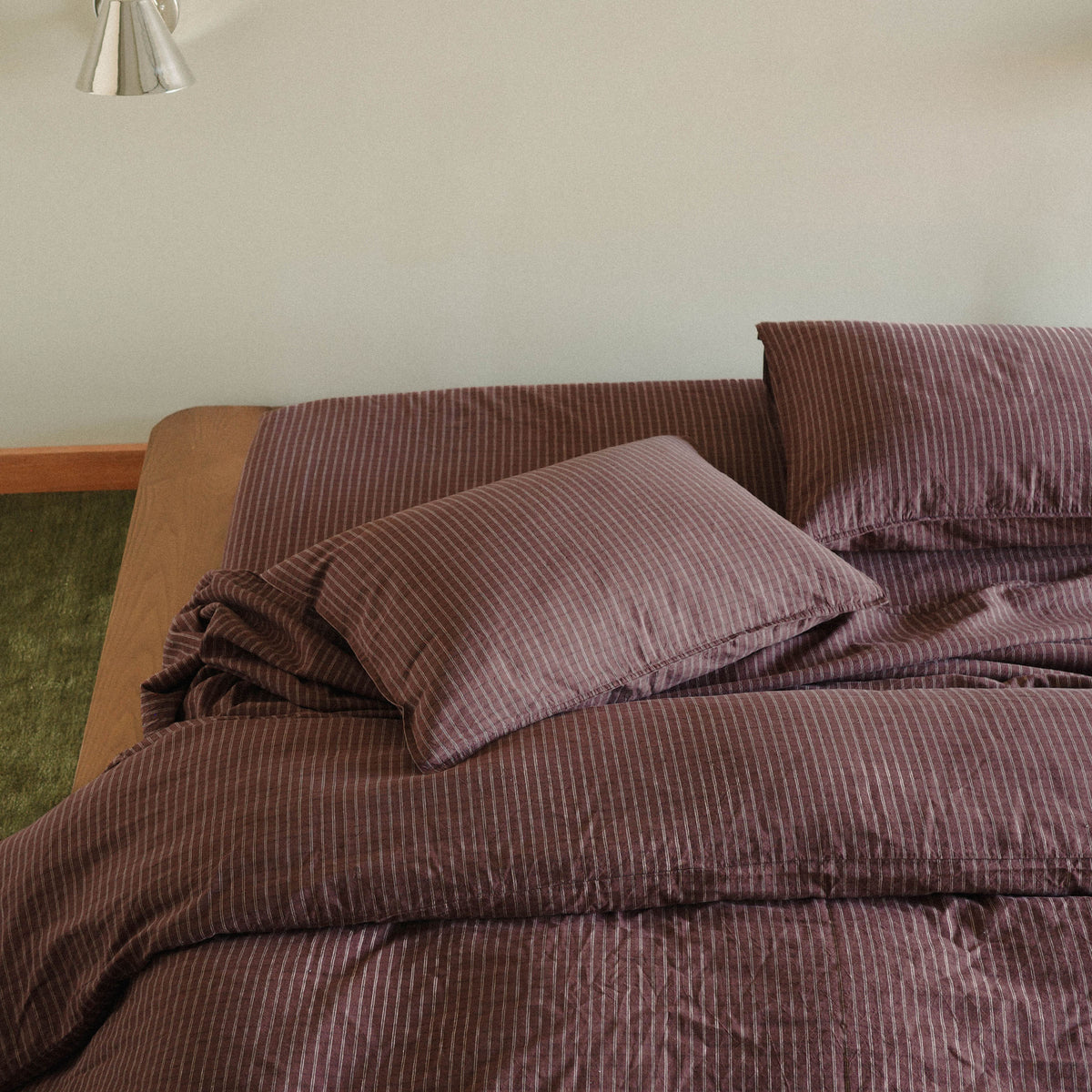 Brown striped bedspread and pillows on a wood bed