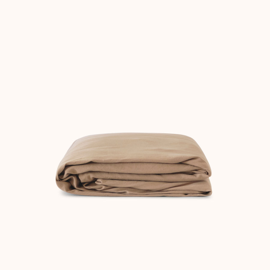 Folded beige fitted sheet on a white background