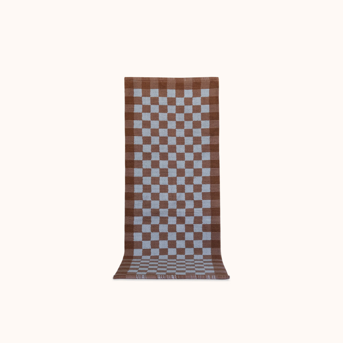 A long rectangular woven mat with a brown and light blue checkerboard pattern, displayed flat against a solid off-white background.