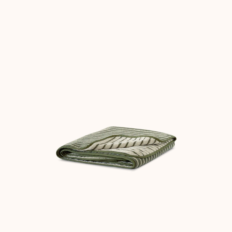 Folded striped terry bath towel in green and beige colors