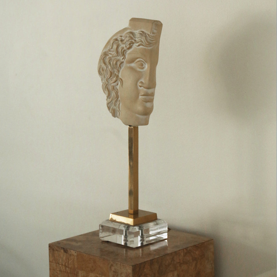 Beige ceramic bust on a light brown pedestal. 