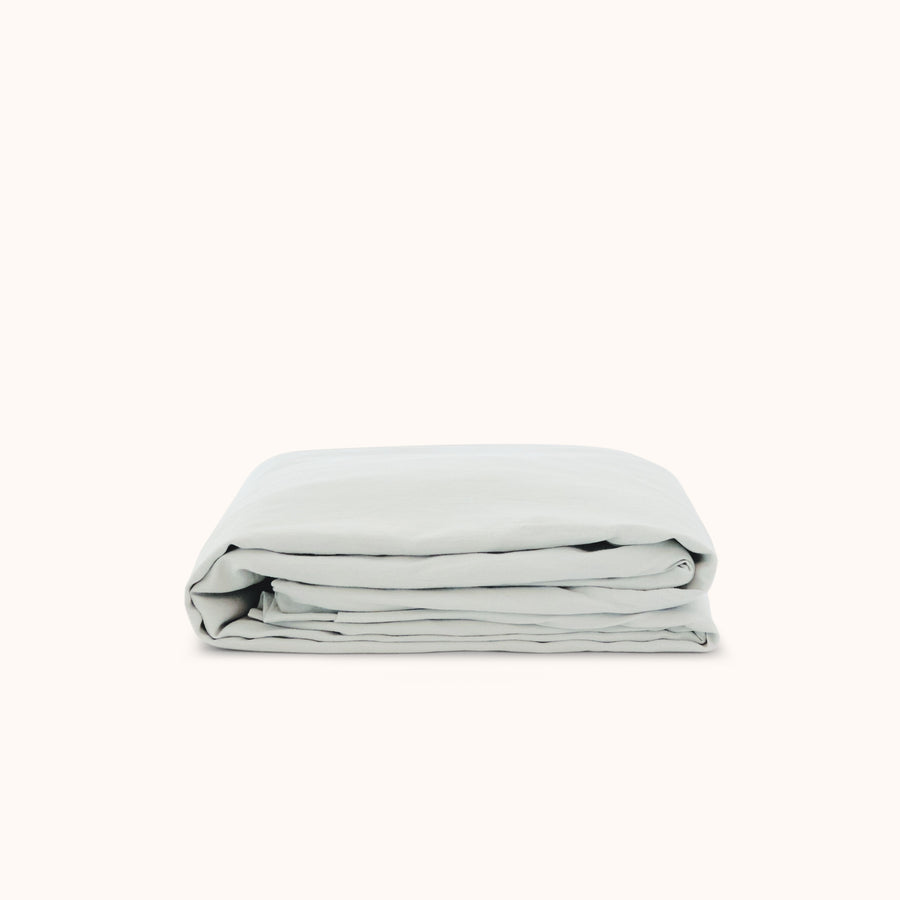 A folded pale blue / Mist fitted sheet made of organic cotton, displayed on a white background.