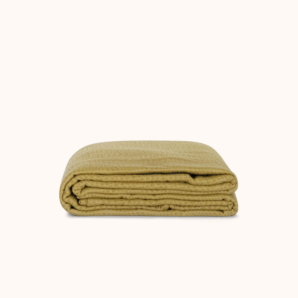 Folded green coverlet on a white background