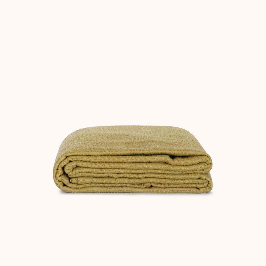 Folded green coverlet on a white background