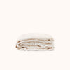 Folded cream fitted sheet on a white background