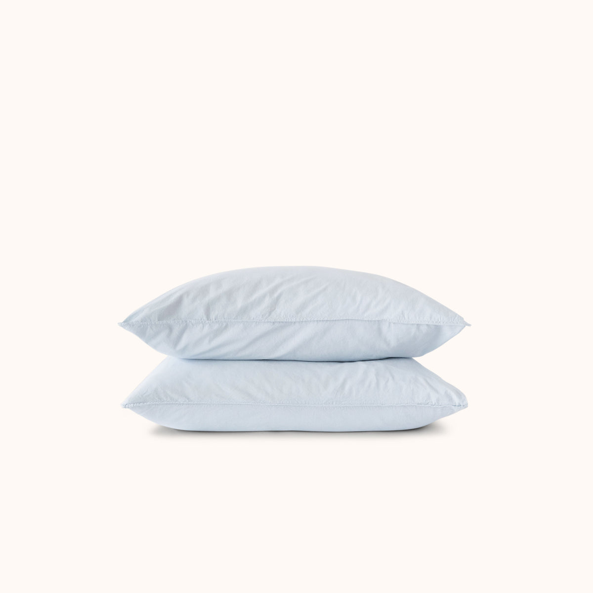 Two light blue pillows stacked on a white background