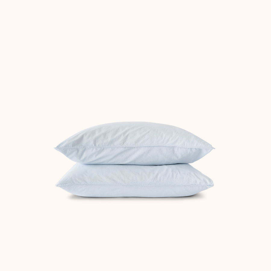 Two light blue pillows stacked on a white background