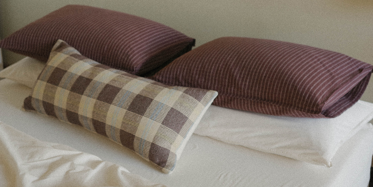 Three pillows on a bed with a neutral background