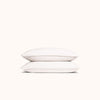 A set of white organic matte sateen pillowcases stacked neatly against a white background