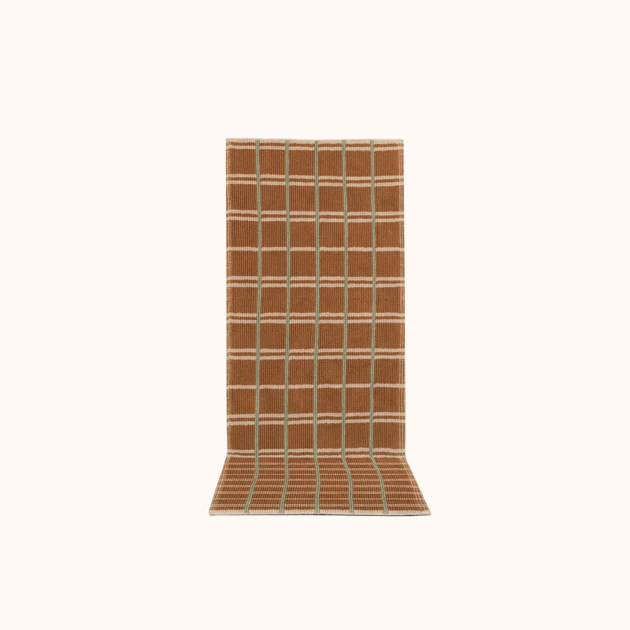 A rectangular runner with a geometric pattern featuring small tight loops, in a hazelnut brown color, with jade and cream accents.